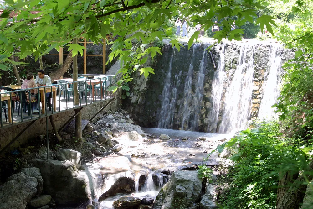 Dere kenarındaki restoran masaları ve şelale