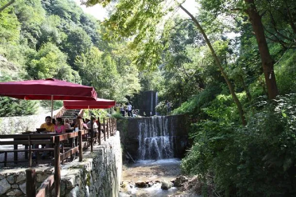 Şelale yanında şemsiyeli restoran terası